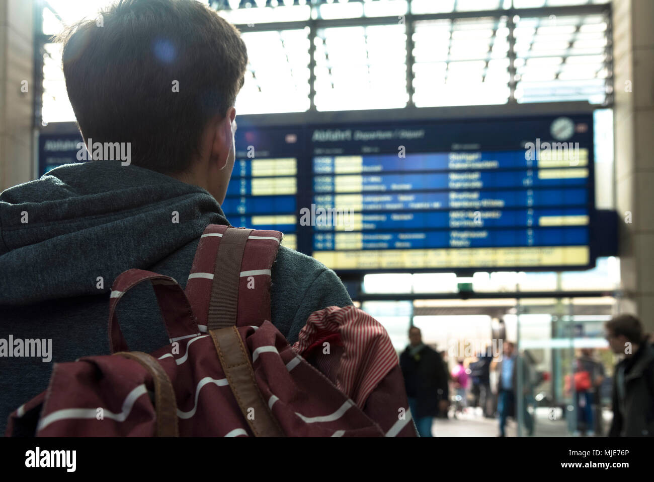 Giovane uomo nella parte anteriore della scheda di destinazione nella stazione ferroviaria Foto Stock