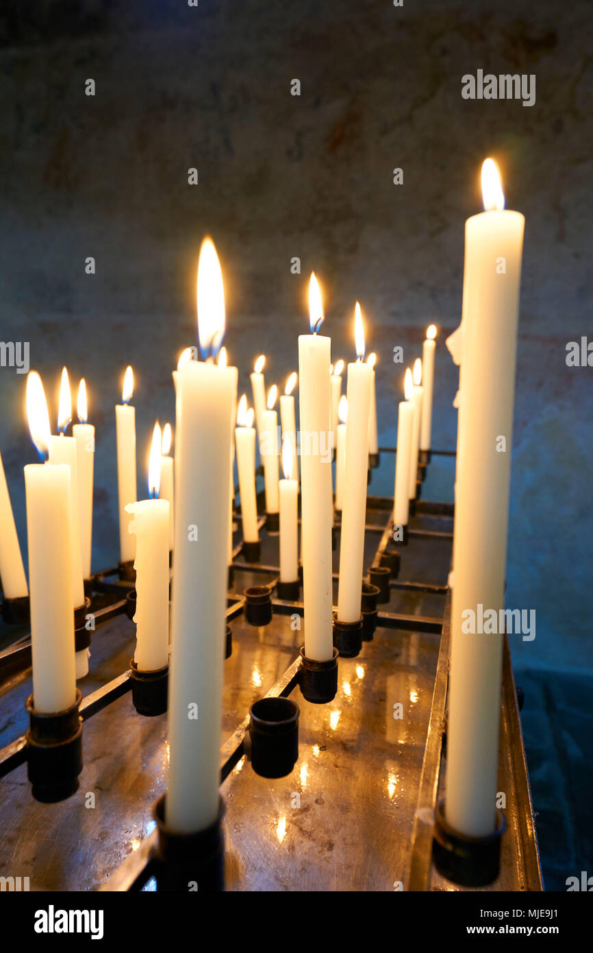 Molte candele bianche sono a bruciare in una chiesa, fianco a fianco, riga Spazio aperto Foto Stock