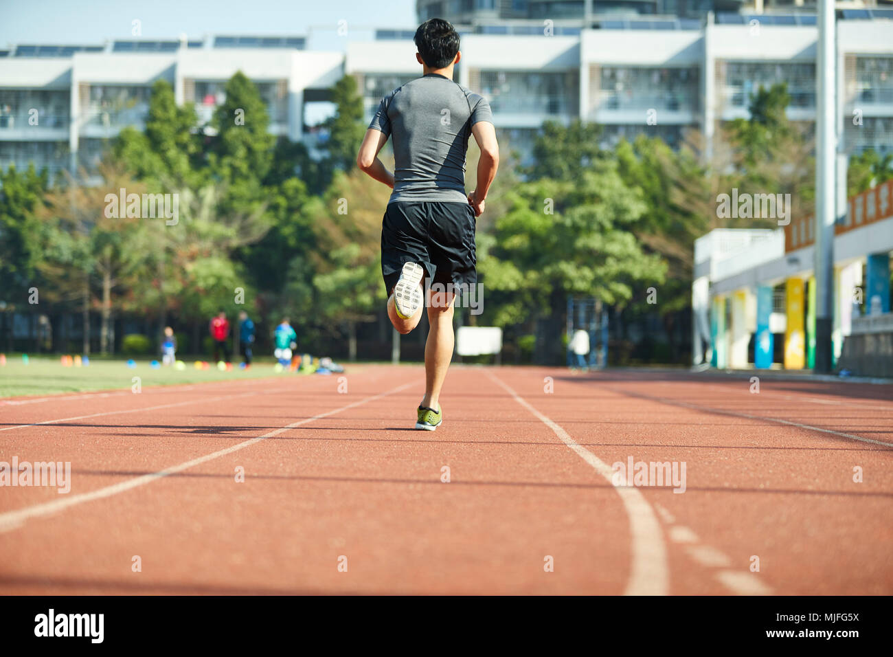 Giovane uomo asiatico atleta maschio esegue la formazione esercita sulla via, in vista posteriore Foto Stock