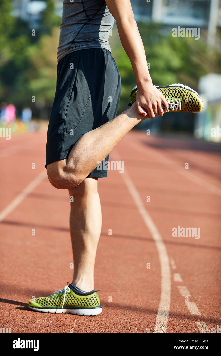 Giovane uomo asiatico atleta maschio in fase di riscaldamento stretching gambe sulla via. Foto Stock