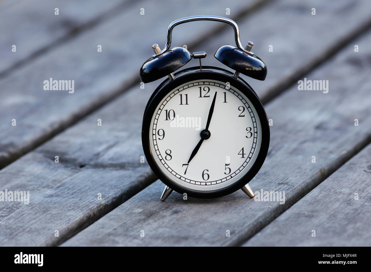 Allarme nero orologio con quadrante bianco su un tavolo showsa pochi minuti trascorsi sette. Foto Stock Allarme nero orologio con quadrante bianco su un tavolo showsa pochi minuti trascorsi sette. Foto Stock