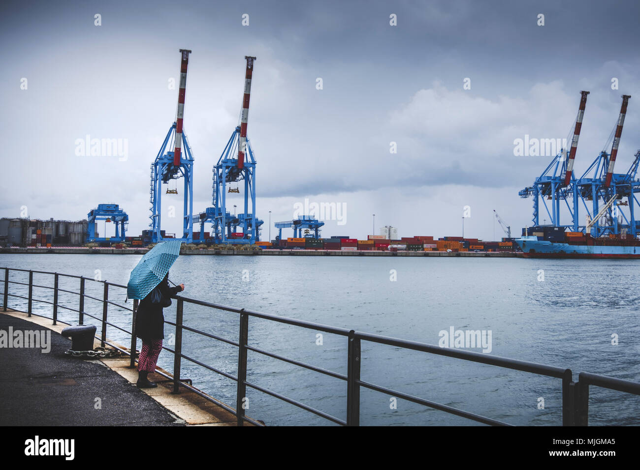 Melanconica scena lonely donna ombrello guardare al porto di Genova rainy Foto Stock