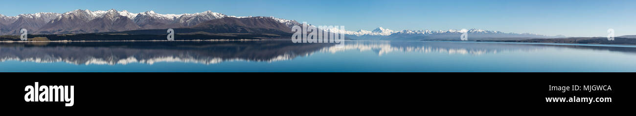 Extra ampio panorama di Monte Cook e circostanti cime coperte di neve si riflette nelle acque blu del lago Taupo, Nuova Zelanda Foto Stock