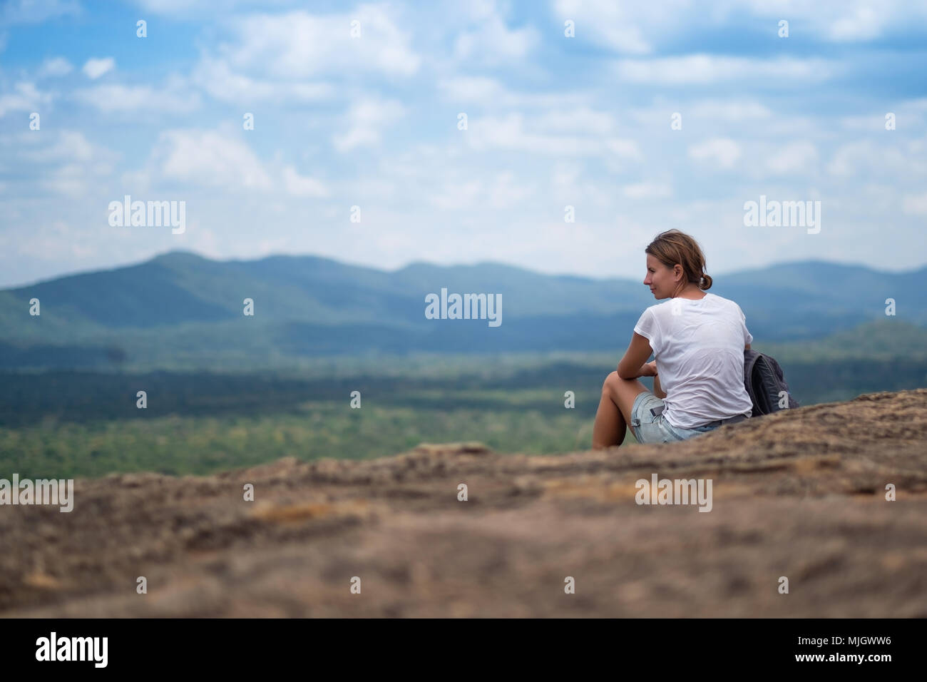 Giovane donna con zaino seduto sulla montagna e in cerca di un cielo di nuvole. La splendida natura dello Sri Lanka Foto Stock