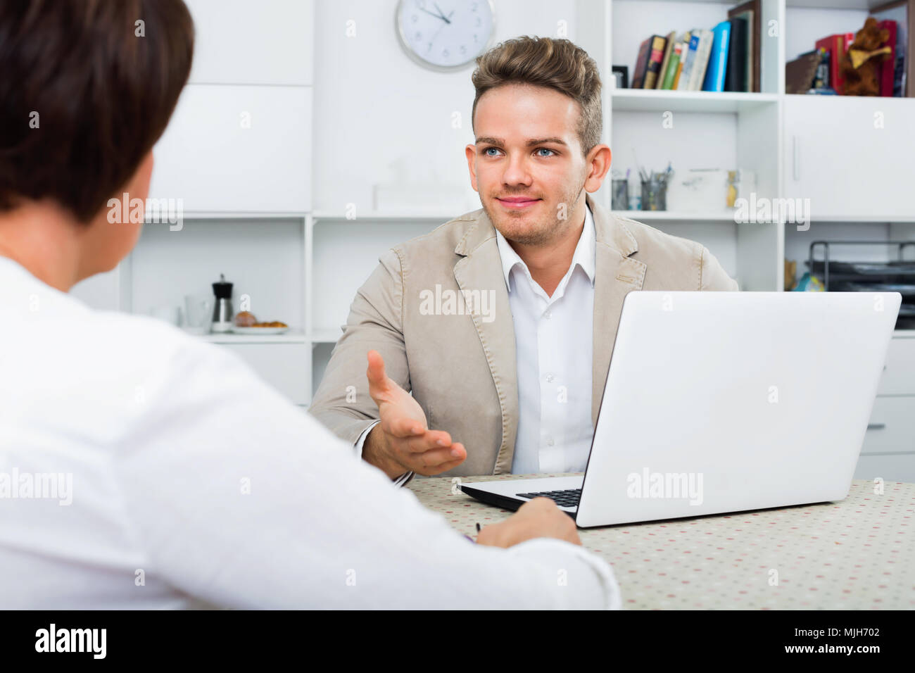 Il giovane giornalista sorridente con notebook bianco interviste agli anziani ricchi donna Foto Stock