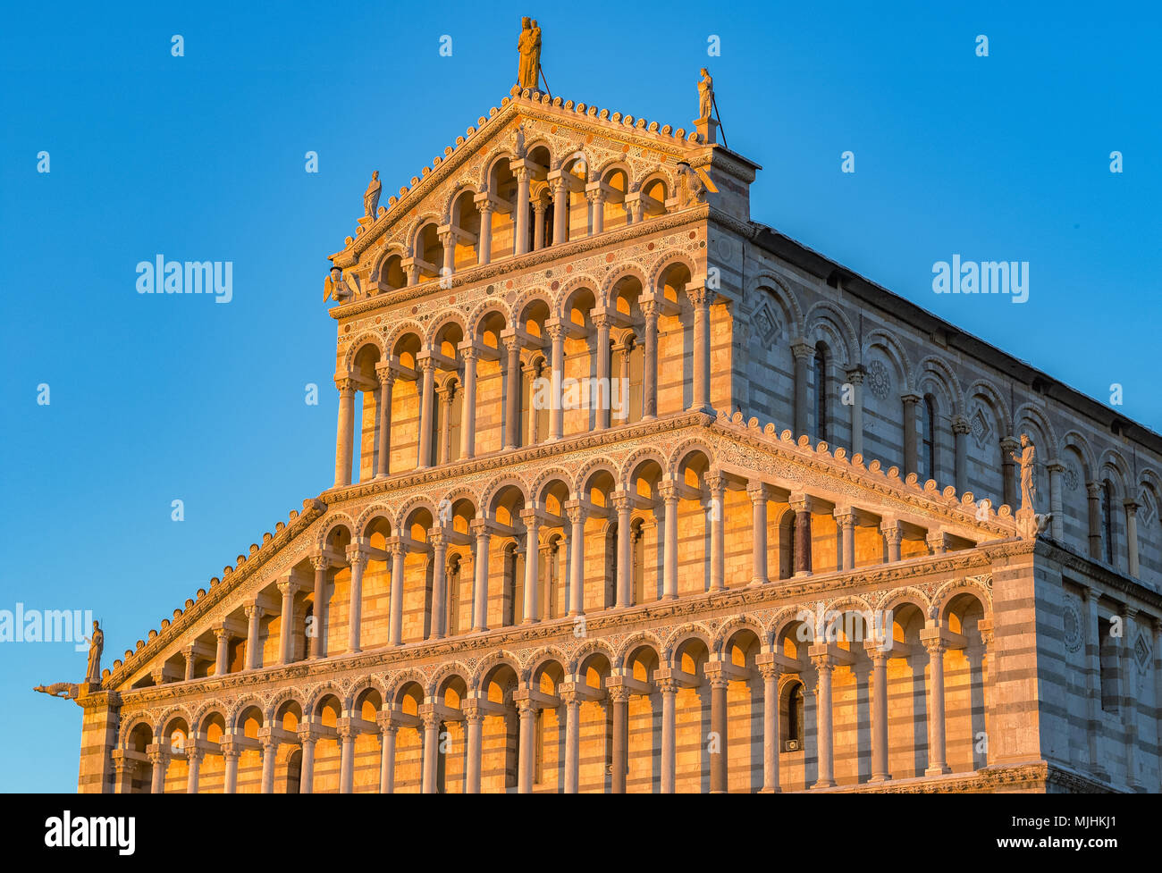 Golden ha colpito la luce solare sulla facciata del Duomo di Pisa in Italia al tramonto contro un cielo privo di nuvole Foto Stock