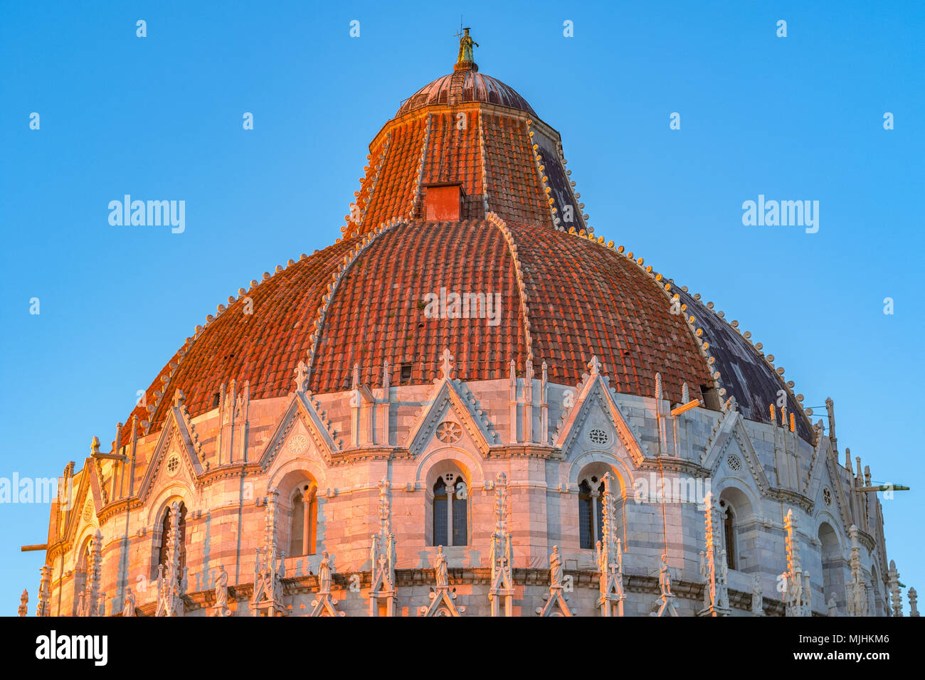 Luce del sole dorato hit della cupola del Battistero di Pisa in Italia al tramonto contro un cielo privo di nuvole Foto Stock