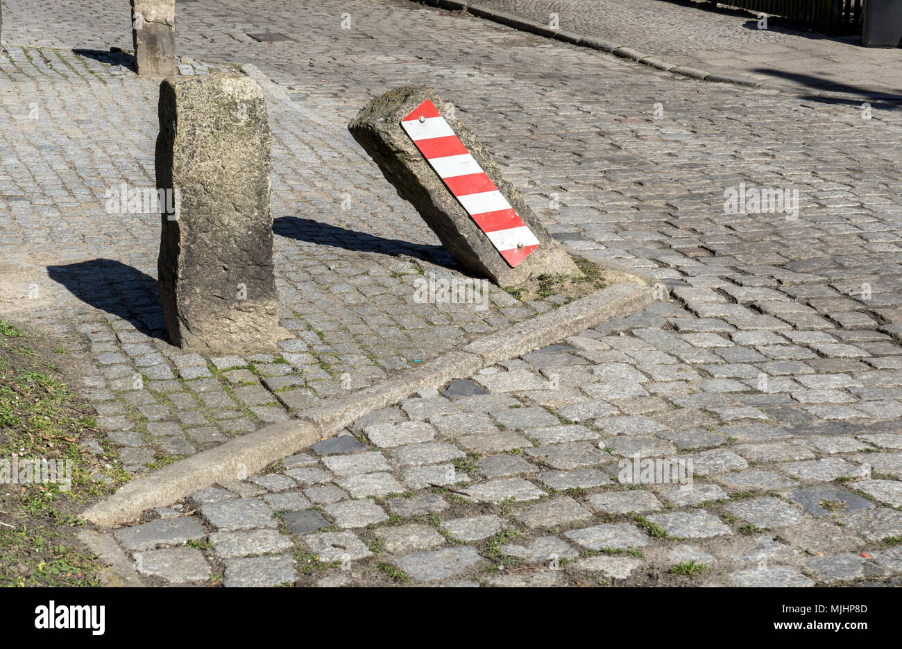 Pietra obliqua su strada con strisce di avvertenza Foto Stock