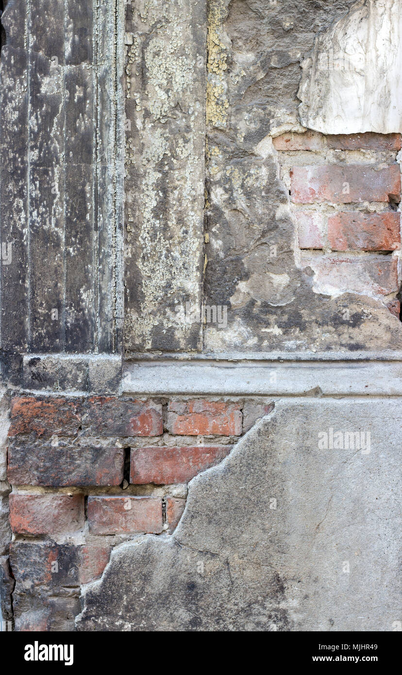 Particolare di una facciata vecchia, grigia, dilatata con mattoni Foto Stock
