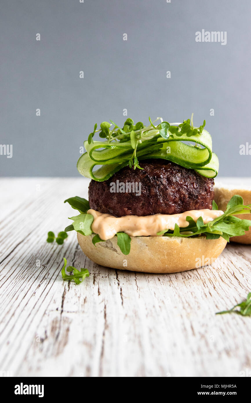 Welsh bistecca hamburger di manzo su pane Bun con Rucola, Nandos Perinaise e nastri di cetriolo Foto Stock
