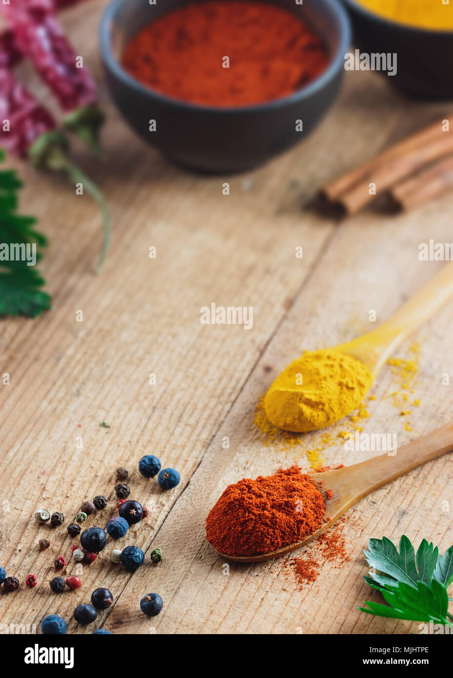 Cucchiaio di legno riempita con la paprika su tavola in legno rustico. Vari ingredienti sul tavolo. Foto Stock