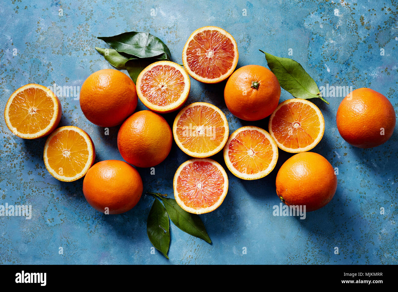 Arance di sangue intero e a fettine su una superficie di colore blu (visto dal di sopra). Foto Stock