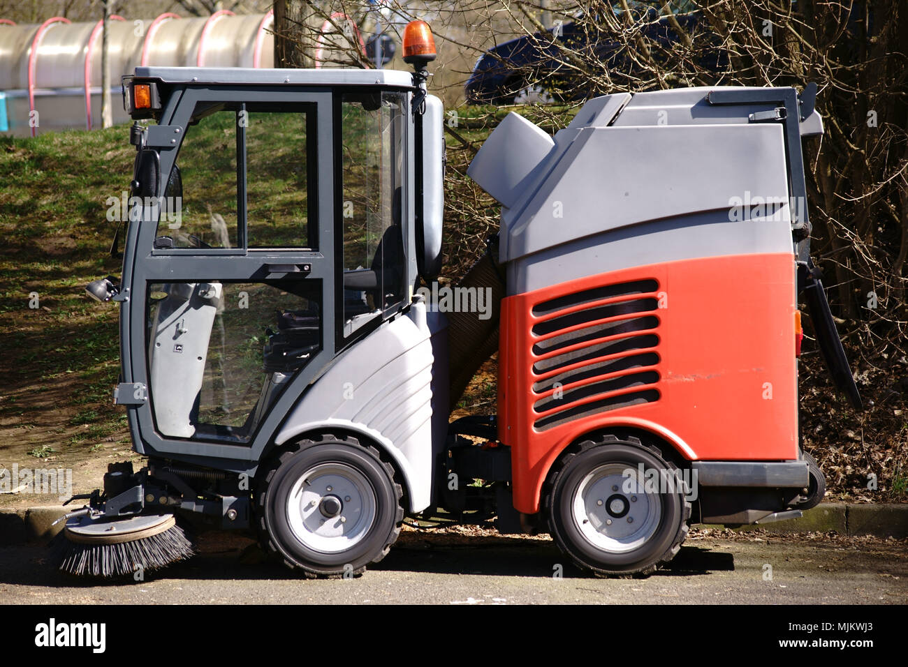 La vista laterale di una piccola strada veicolo di pulizia con una spazzola ed una cabina del conducente con visibilità totale. Foto Stock