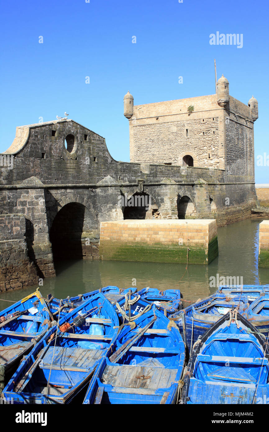 Barche da pesca nel porto di Essaouira contro il fondale di Cittadella Foto Stock