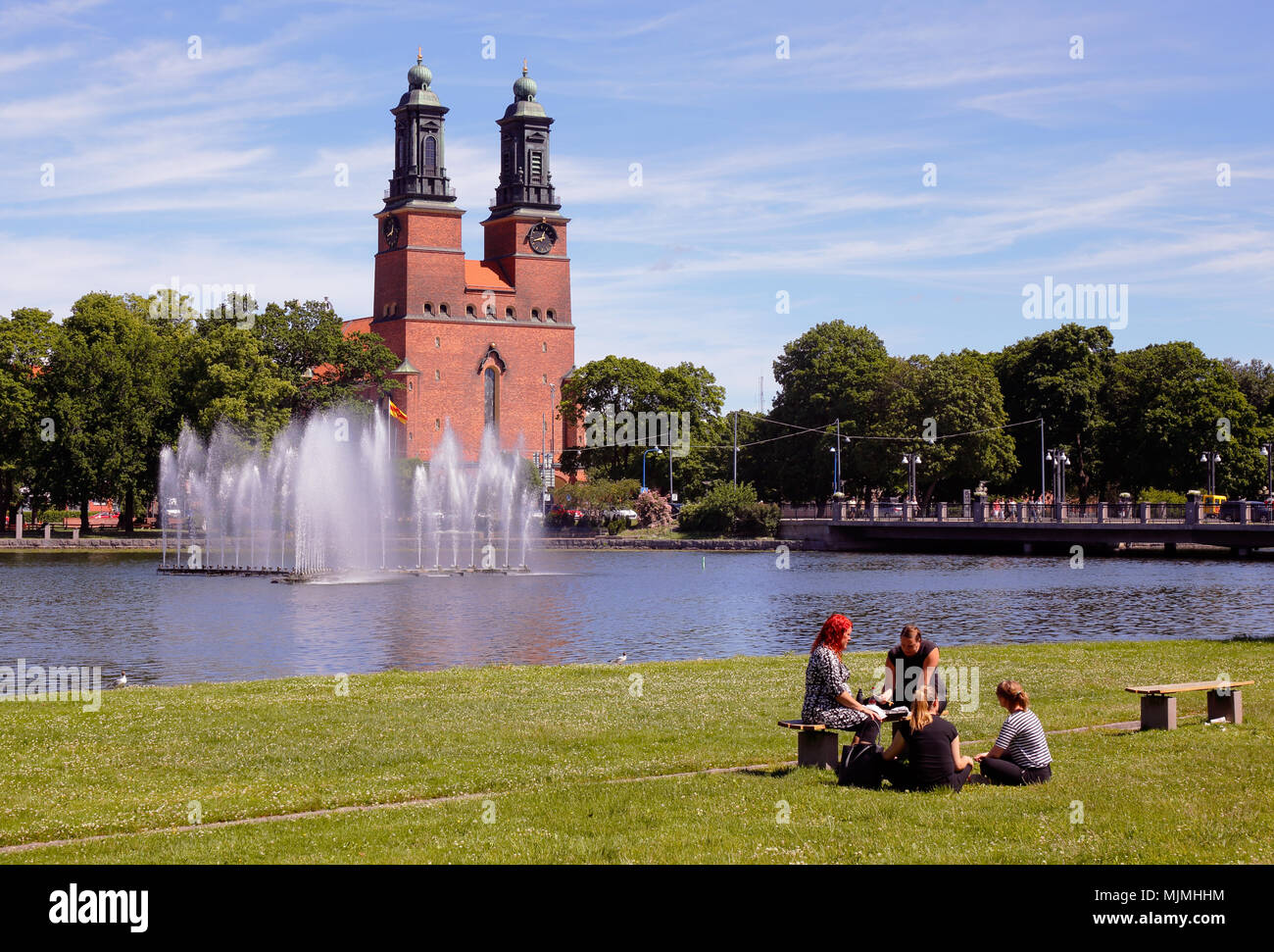 Eskilstuna, Svezia - 19 Giugno 2017: un gruppo di quattro persone sedute nel parco presso il lungomare nel centro cittadino di Eskilstuna con la chiesa di Klosters in th Foto Stock