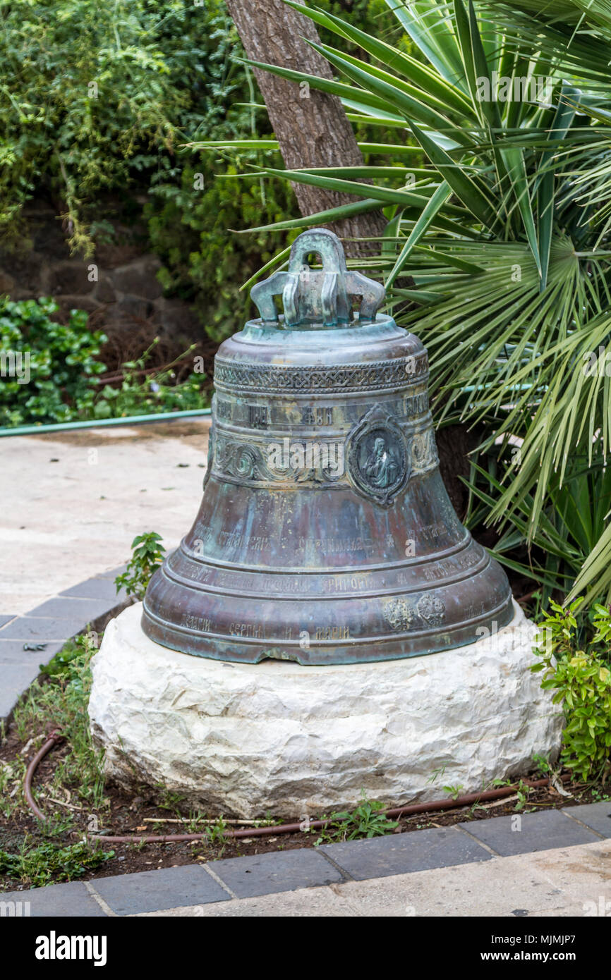Campana con patina e alfabeto cirillico nel giardino della Chiesa Ortodossa Greca dei dodici apostoli a Cafarnao, presso il mare di Galilea, il lago di Tiberiade Foto Stock
