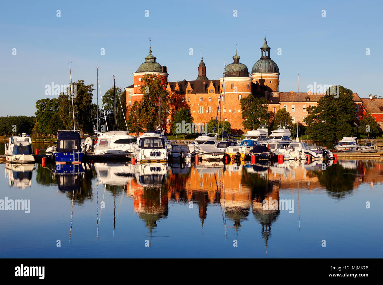 Mariefred, Svezia - 15 agosto 2017: il sole del mattino brilla al Castello di Gripsholm che riflette in acqua vicino alla marina da imbarcazioni da diporto. Foto Stock