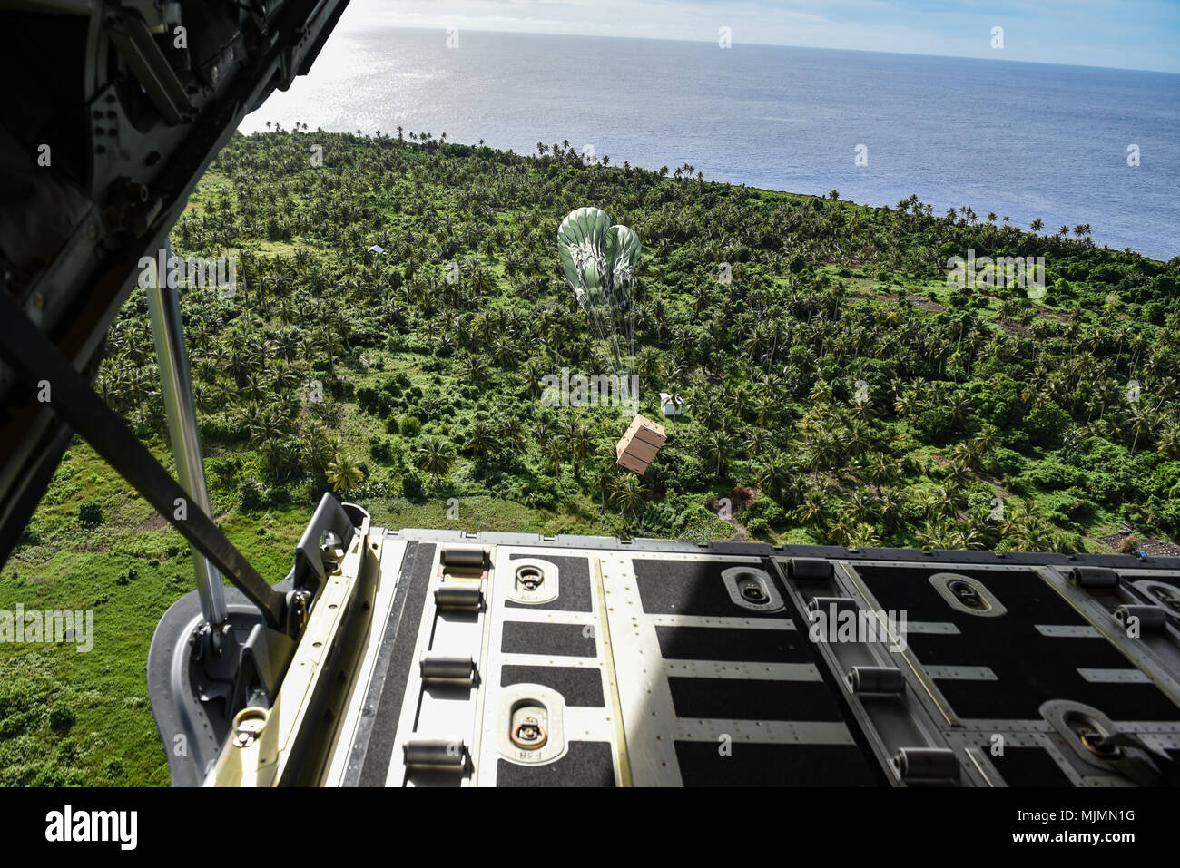 Un pacchetto con beni donati sospesi da un paracadute cade da una C-130J Super Hercules durante il funzionamento caduta di Natale dic. 11, 2017 sopra l'isola di Fais. Caduta di Natale è la più lunga del mondo in funzione airdrop missione. Per il terzo anno di fila, U.S., il giapponese e il personale di volo australiano addestrato a fianco di ogni altro mentre la fornitura di materiali di consumo critico di 56 isole della Micronesia incidono circa 20.000 persone e copre 1,8 milioni di mq miglia nautiche di area operativa. Il C-130 è assegnato alla XXXVI Airlift Squadron a Yokota Air Base, Giappone. (U.S. Air Force photo by Staff Sgt. Alexander W Foto Stock