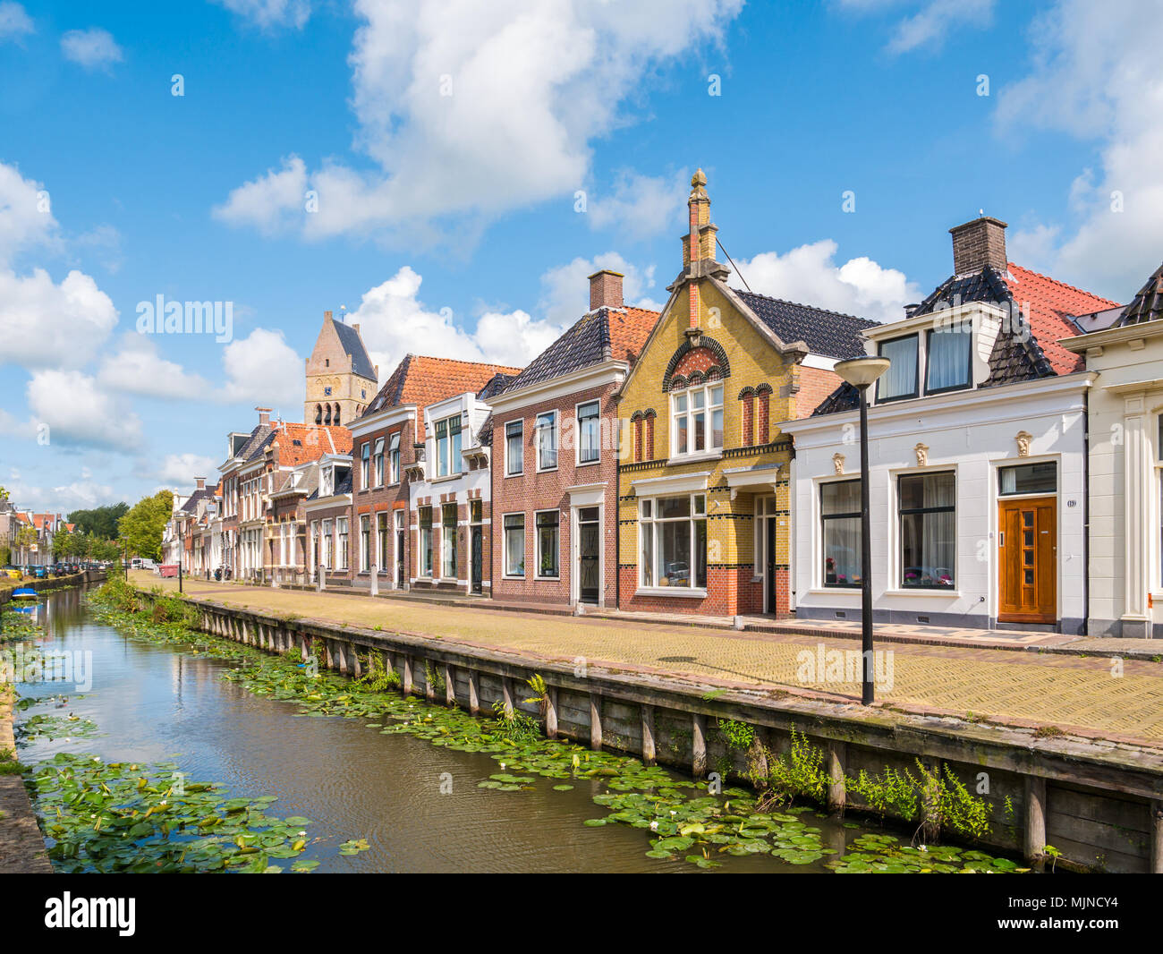 Scena di strada di Kleine Dijlakker canal e la torre della chiesa protestante nella vecchia città di Bolsward, Friesland, Paesi Bassi Foto Stock
