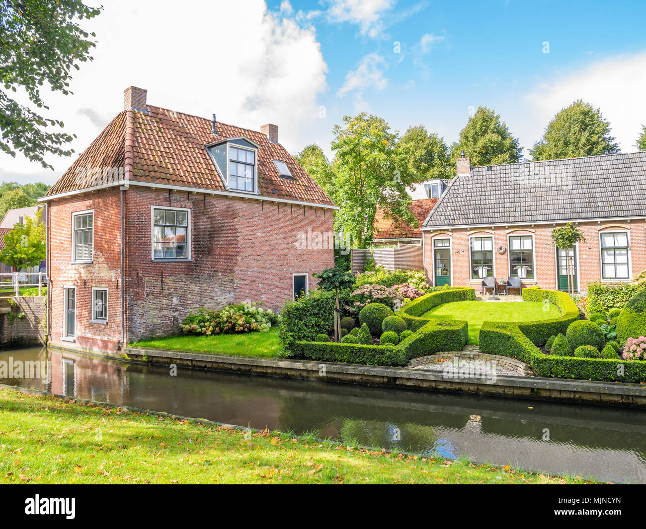 Scena di strada di Oranjewal canal con waterfront case e giardini nella città vecchia di Dokkum, Friesland, Paesi Bassi Foto Stock