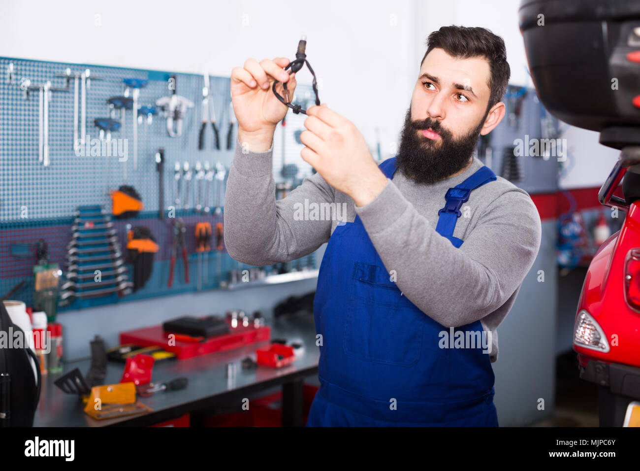 Lavoratore è osservando la parte in moto per il fissaggio in officina. Foto Stock