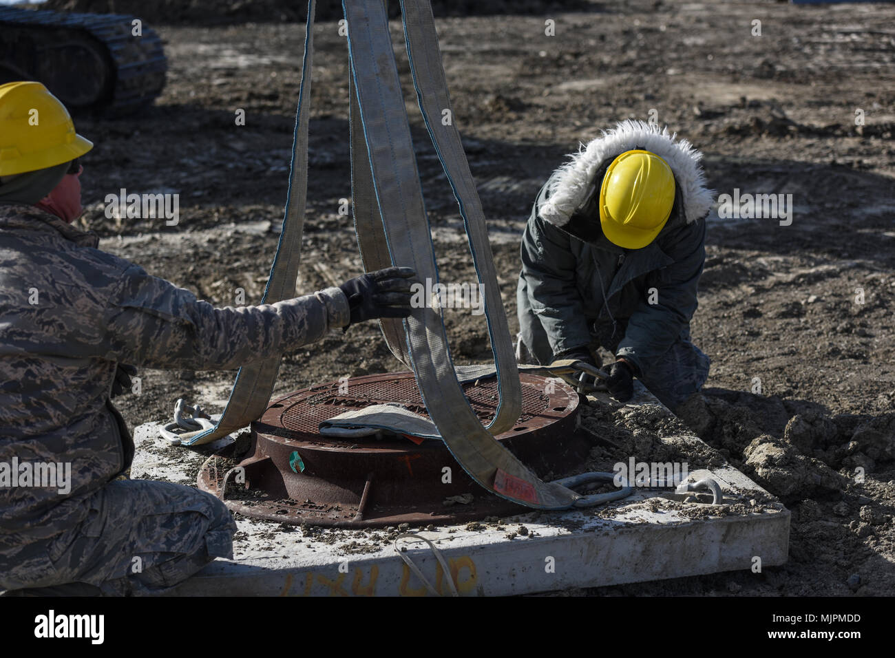 Stati Uniti Air Force Senior Airman Bobby Chambers, sinistra e Staff Sgt. James Terrell, gli studenti che frequentano la Progettazione Installazione veicolo classe di formazione, rig una manutenzione del coperchio del foro per essere sollevati da un escavatore dic. 13, 2017, presso la Air National Guard Schoolhouse, Fort Indiantown Gap, Pennsylvania. Gli aviatori hanno utilizzato tecniche di manovre che hanno appreso in classe di manovra di fori di manutenzione per installazione interrata. (U.S. Air National Guard photo by Staff Sgt. Tony ARPA/rilasciato) Foto Stock