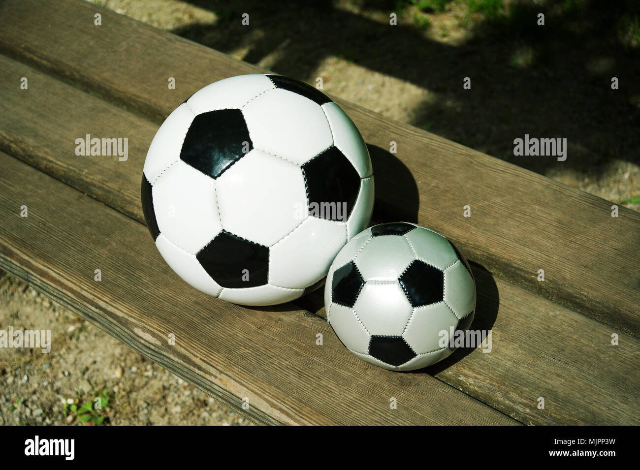 Due palloni da calcio su un parkbench in primavera Foto Stock