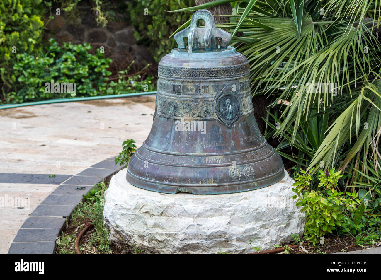 Campana con patina e alfabeto cirillico nel giardino della Chiesa Ortodossa Greca dei dodici apostoli a Cafarnao, presso il mare di Galilea, il lago di Tiberiade Foto Stock