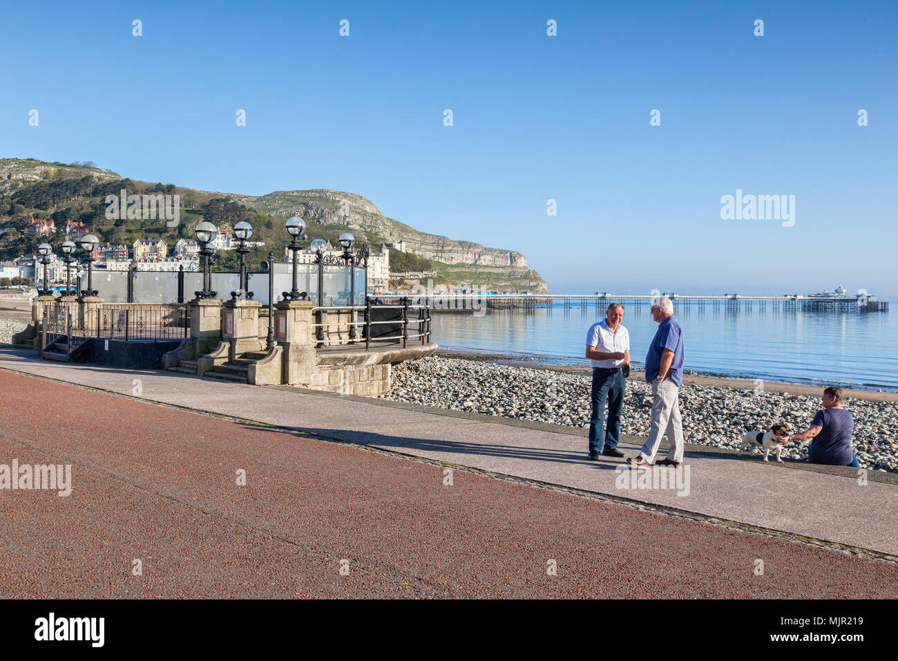 6 Maggio 2018: Llandudno, il Galles del Nord - Senior di uomini in shirt maniche in chat sul lungomare, domenica mattina presto sul soleggiato giorno di maggio weekend. Foto Stock