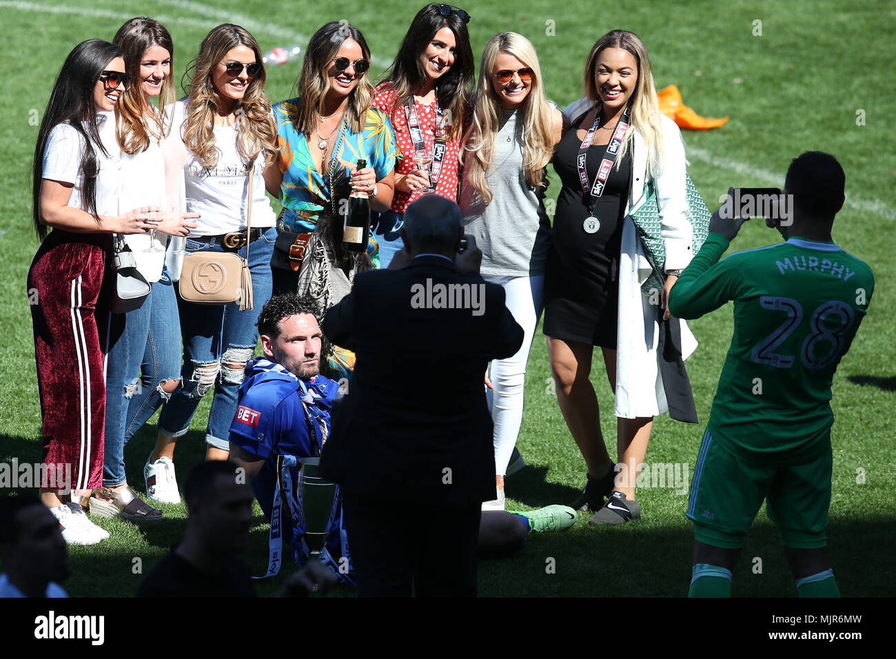 Cardiff, Regno Unito, 6 maggio 2018. Cardiff City capitano Sean Morrison (sul terreno) in posa per una foto con un gruppo di donne /mattacchioni dopo la partita come si celebra il Cardiff's promozione per la Premier League. EFL Skybet partita in campionato, Cardiff City v lettura al Cardiff City Stadium domenica 6 maggio 2018. Questa immagine può essere utilizzata solo per scopi editoriali. Solo uso editoriale, è richiesta una licenza per uso commerciale. Nessun uso in scommesse, giochi o un singolo giocatore/club/league pubblicazioni. pic da Andrew Orchard/Andrew Orchard fotografia sportiva/Alamy Live news Foto Stock