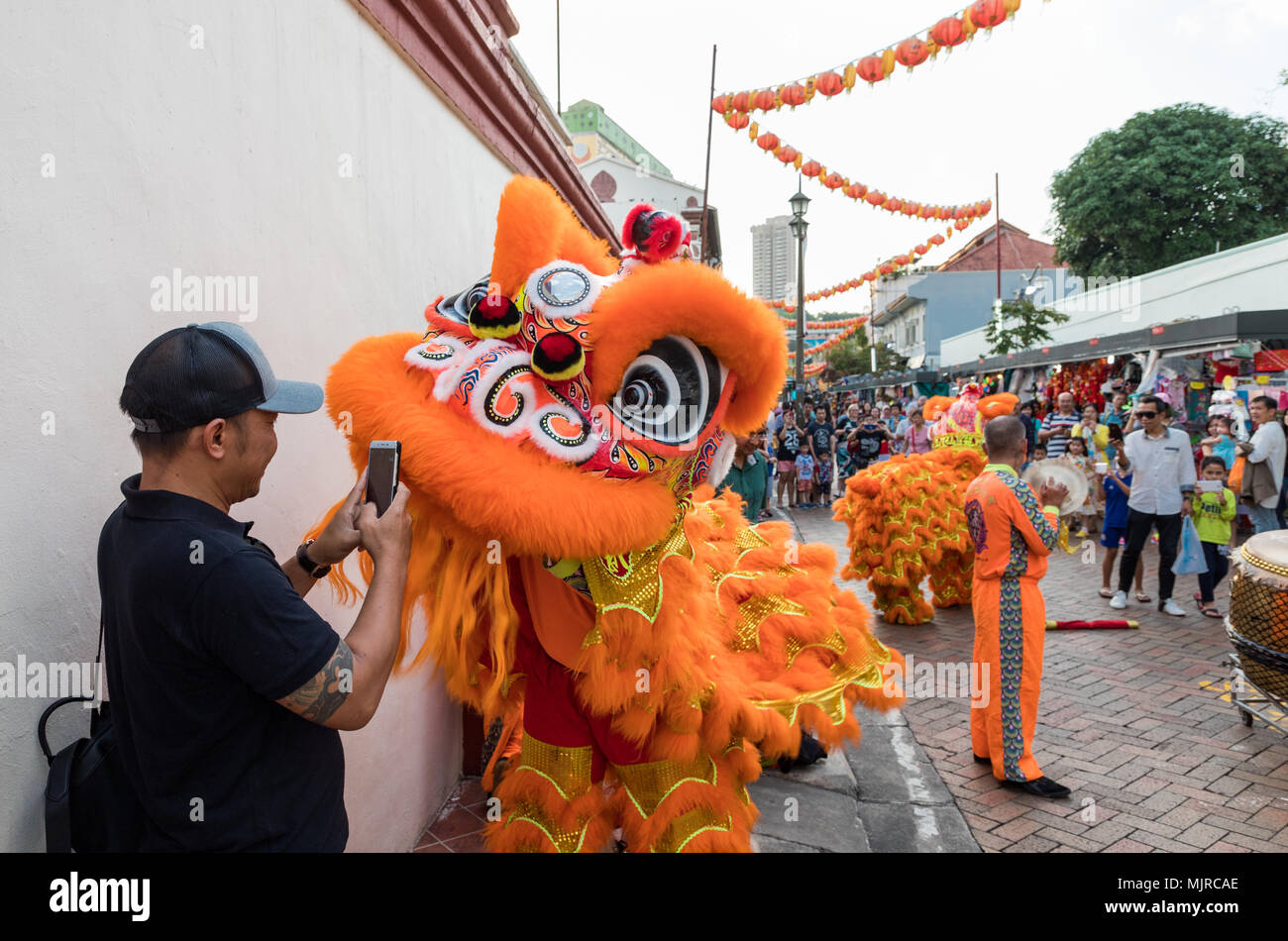 Singapore - Marzo 24, 2018: Un uomo prende una foto da vicino degli artisti interpreti o esecutori in costume tradizionale eseguendo il cinese la danza del leone, Chinatown Foto Stock