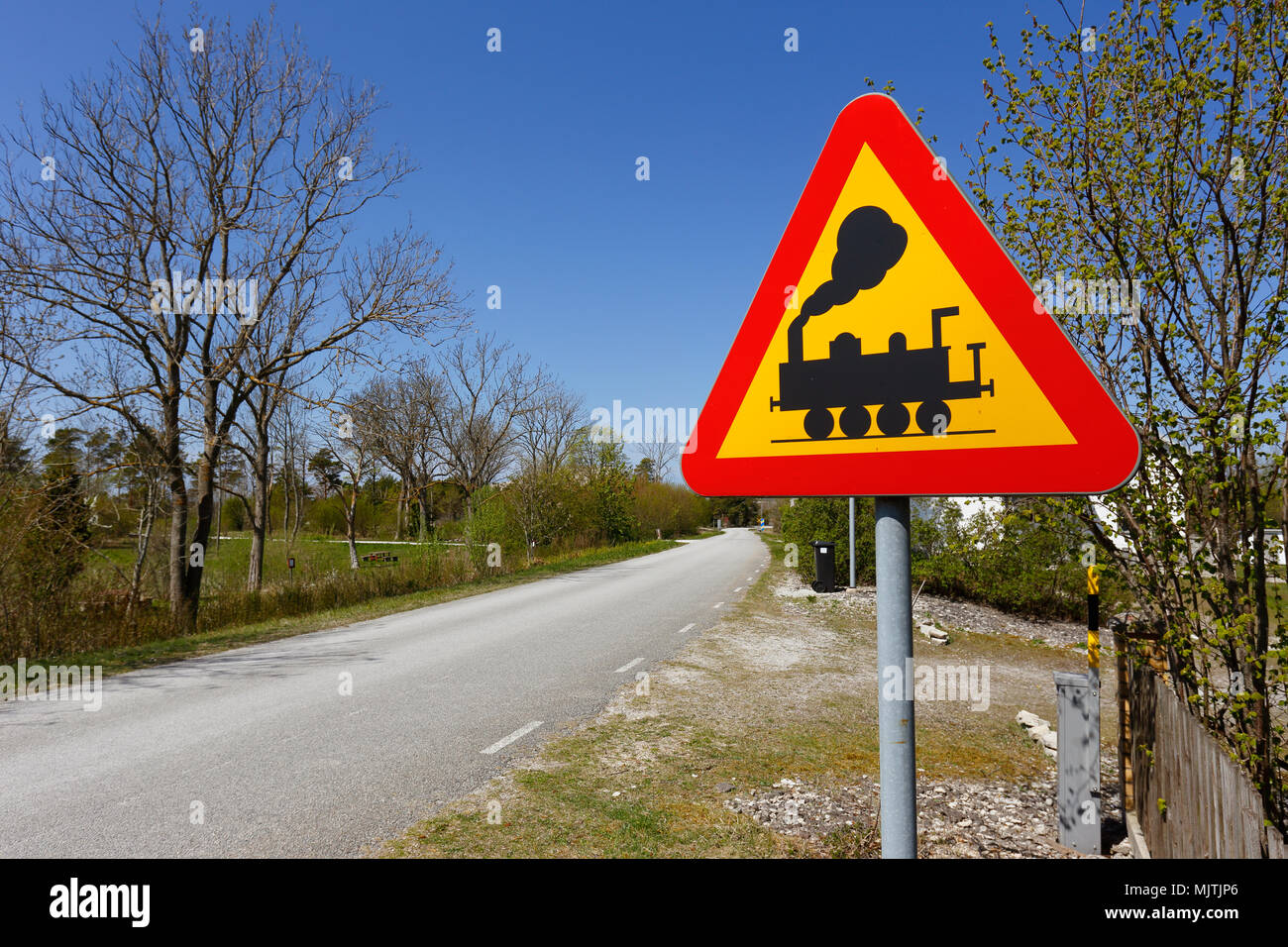 Svedese di cartello stradale passaggio a livello senza porte davanti al lato di una strada stretta. Foto Stock