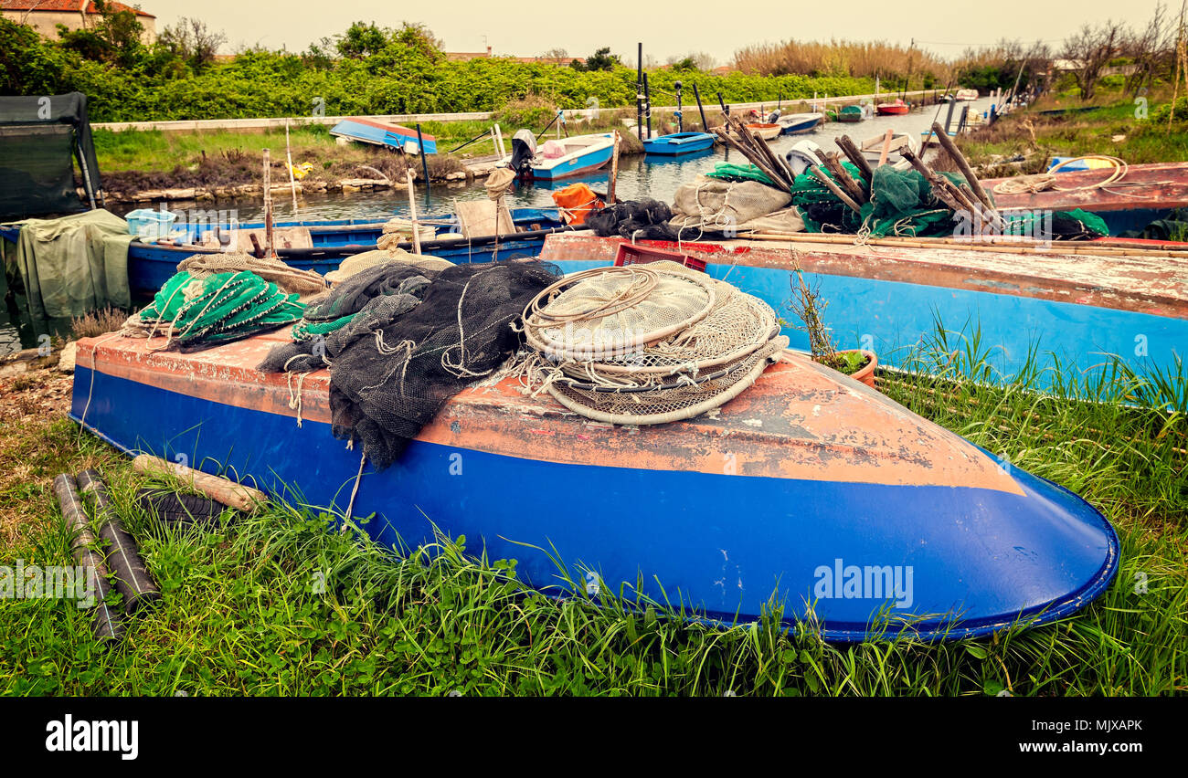 La pesca in barca rovesciata sulla riva con reti da pesca ad asciugare Foto Stock