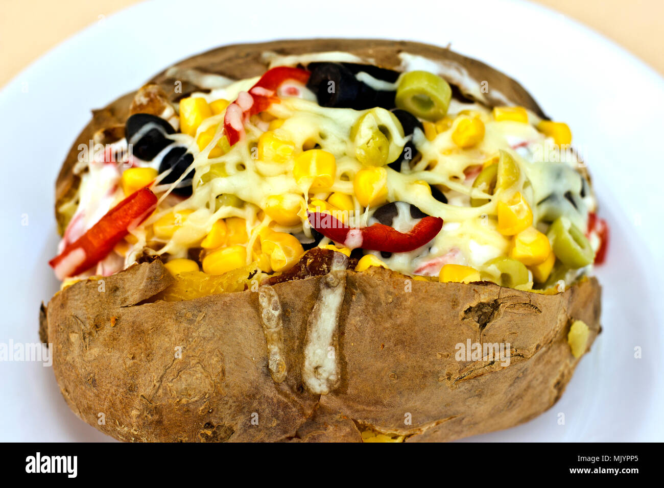 Kumpir cotto ripieno di patate con formaggio, salsicce, olive, peperoni e mais Foto Stock