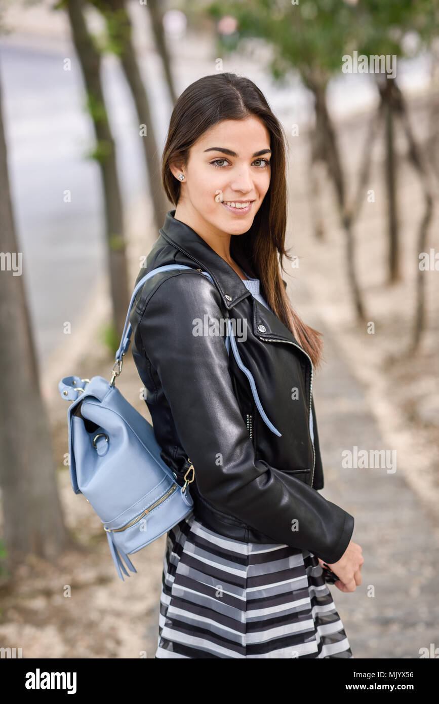 Ritratto di giovane donna sorridente in background urbano di indossare un  abbigliamento informale. Ragazza indossare gonna a strisce, maglione e  giacca di pelle Foto stock - Alamy