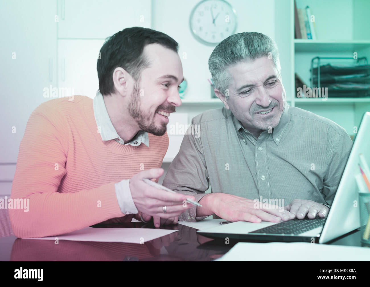 Sorridente per adulti e giovani lavoratori guardando interessanti su Internet al computer Foto Stock