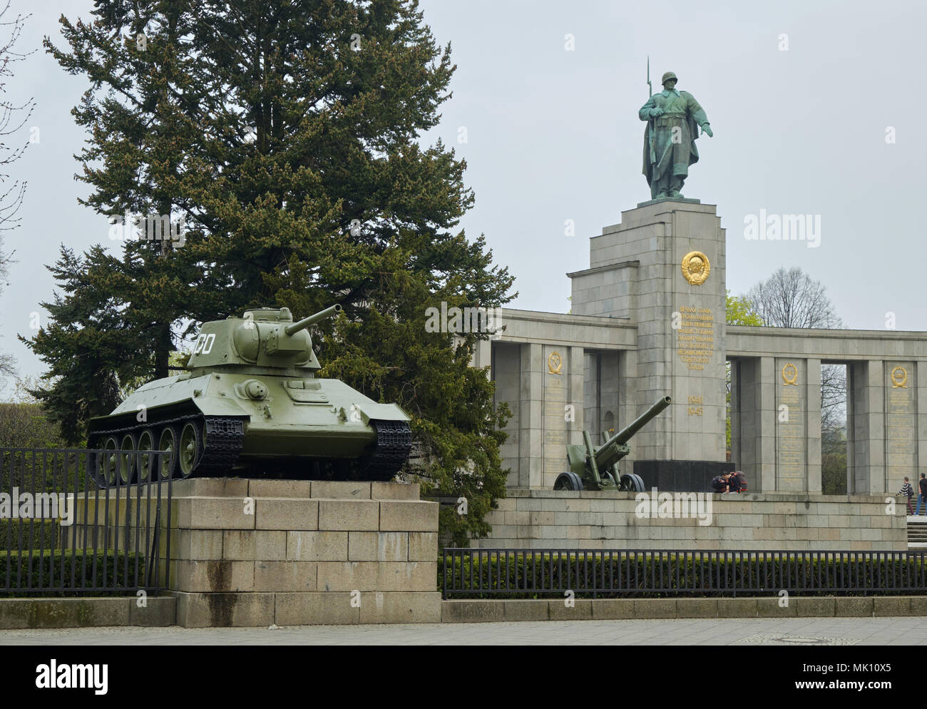 Berlino, Germania - 14 Aprile 2018: carro armato sovietico T-34 e cannone di artiglieria con statua del soldato sovietico e pino sullo sfondo a guerra sovietica Memori Foto Stock