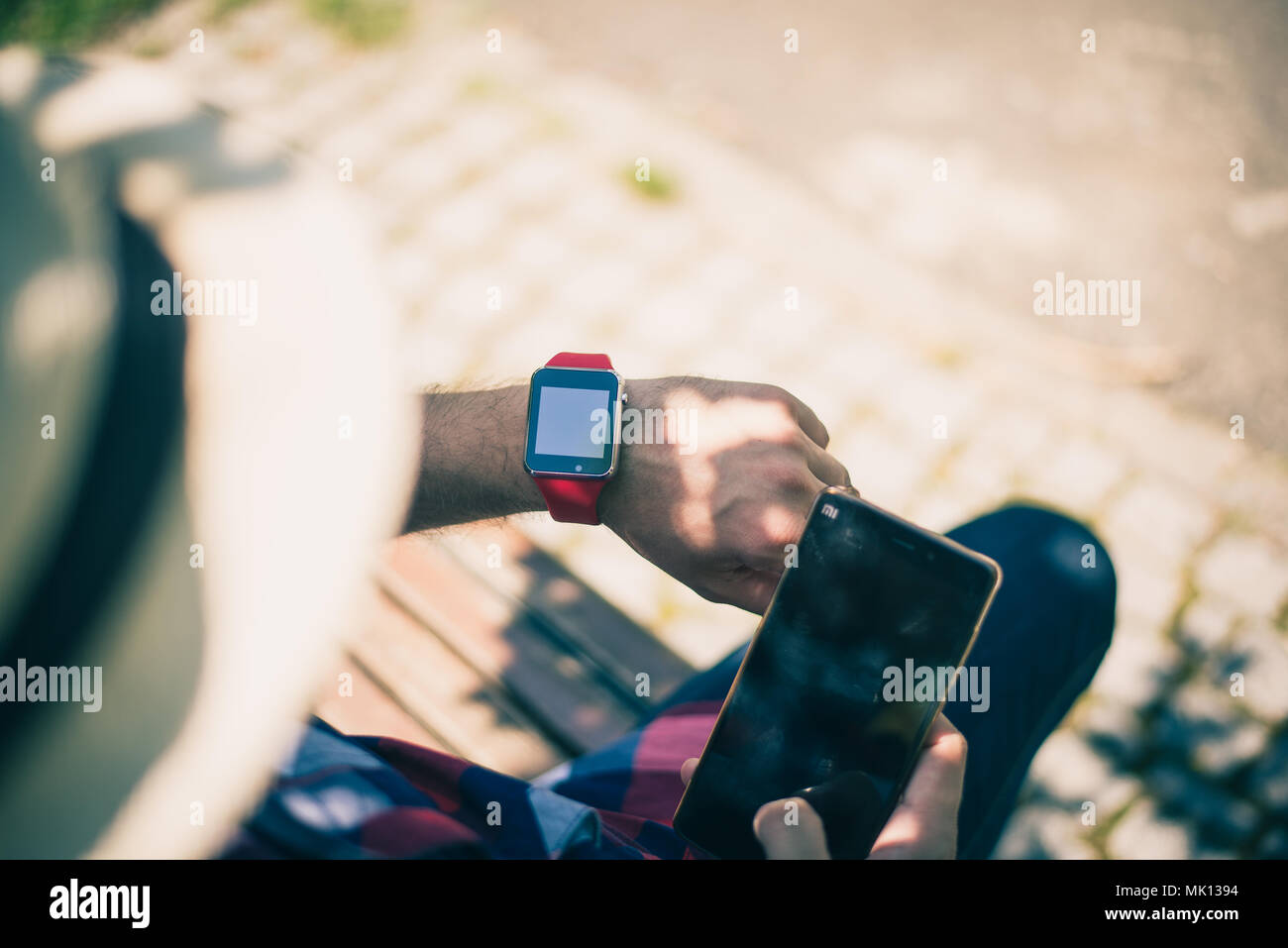Bucarest, Romania - 26 Ottobre 2017: Persona utilizzando smart watch e uno smartphone a piedi per il parco in una domenica. Giovane uomo compiendo gesti su una usura Foto Stock