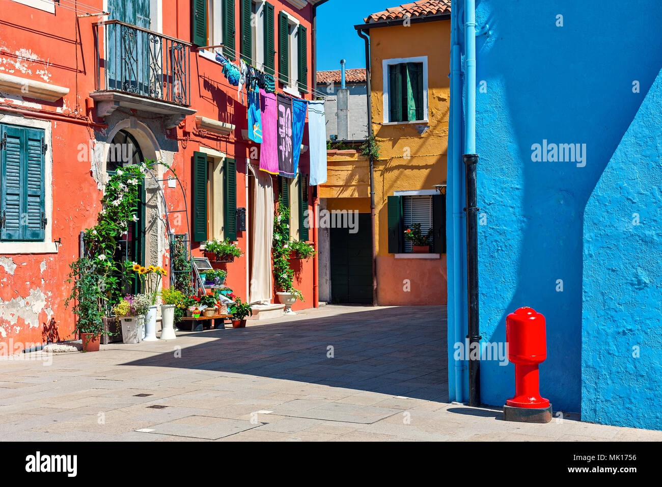 Rosso, arancio e blu case lungo strada stretta nella famosa cittadina di Burano, Italia. Foto Stock