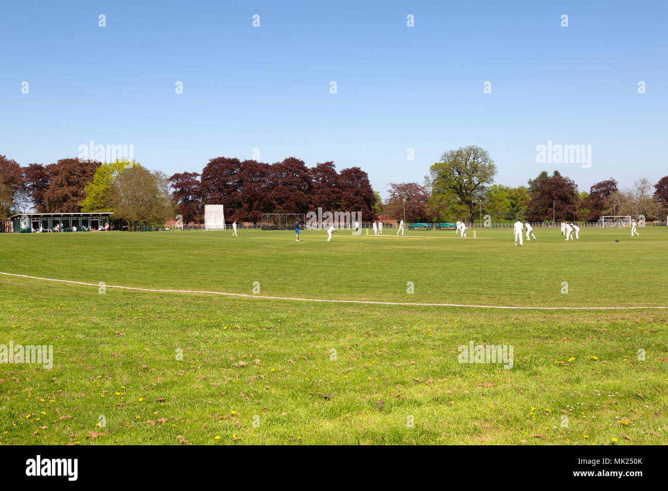 Una partita di cricket in un inglese un campo di cricket in Enville, Staffordshire, in estate, mostrando il cricket pavilion sulla sinistra. Foto Stock