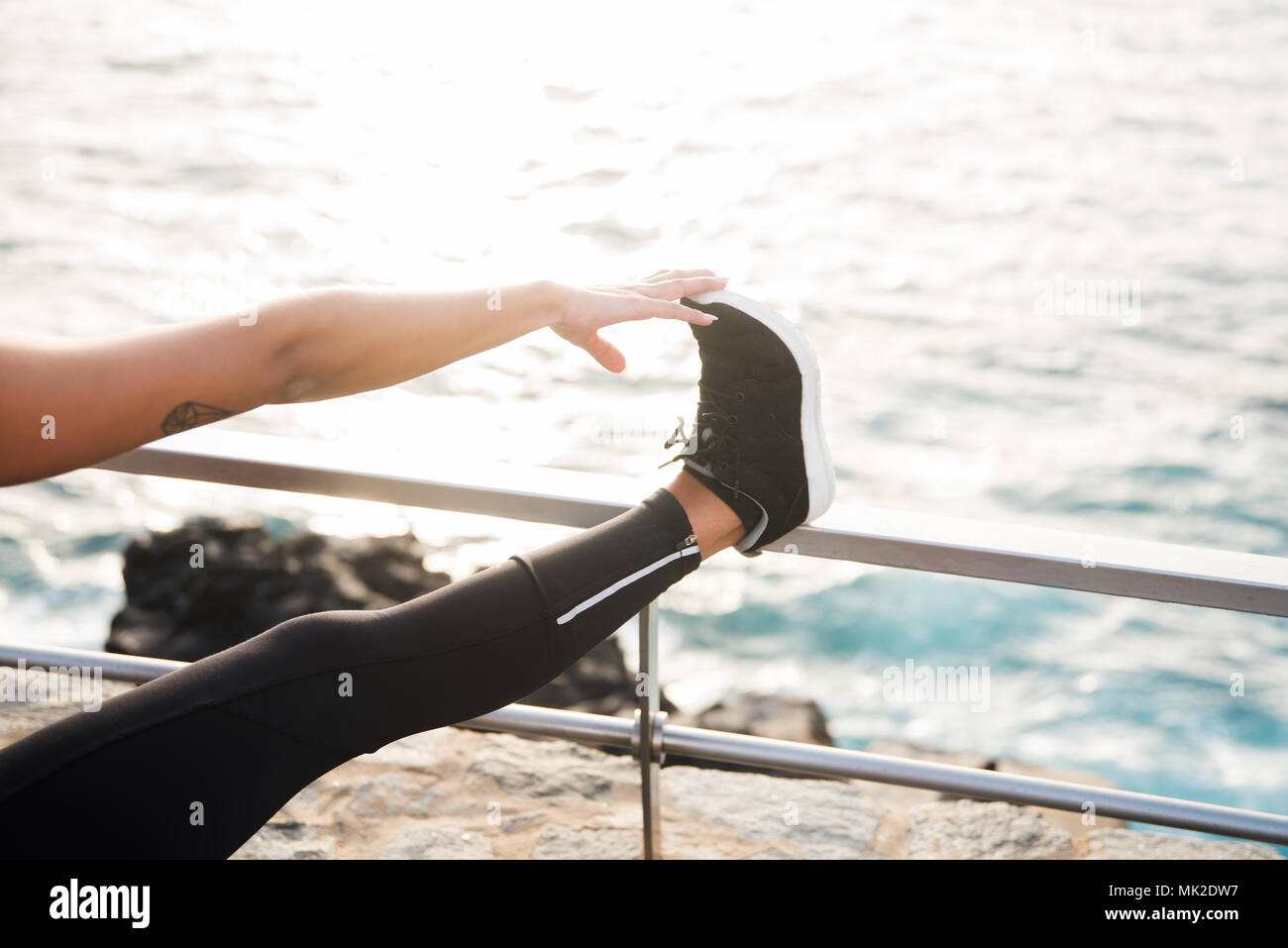Una signora in collant di toccare la sua dita dei piedi con la sua gamba in  alto su una ringhiera in riva al mare Foto stock - Alamy