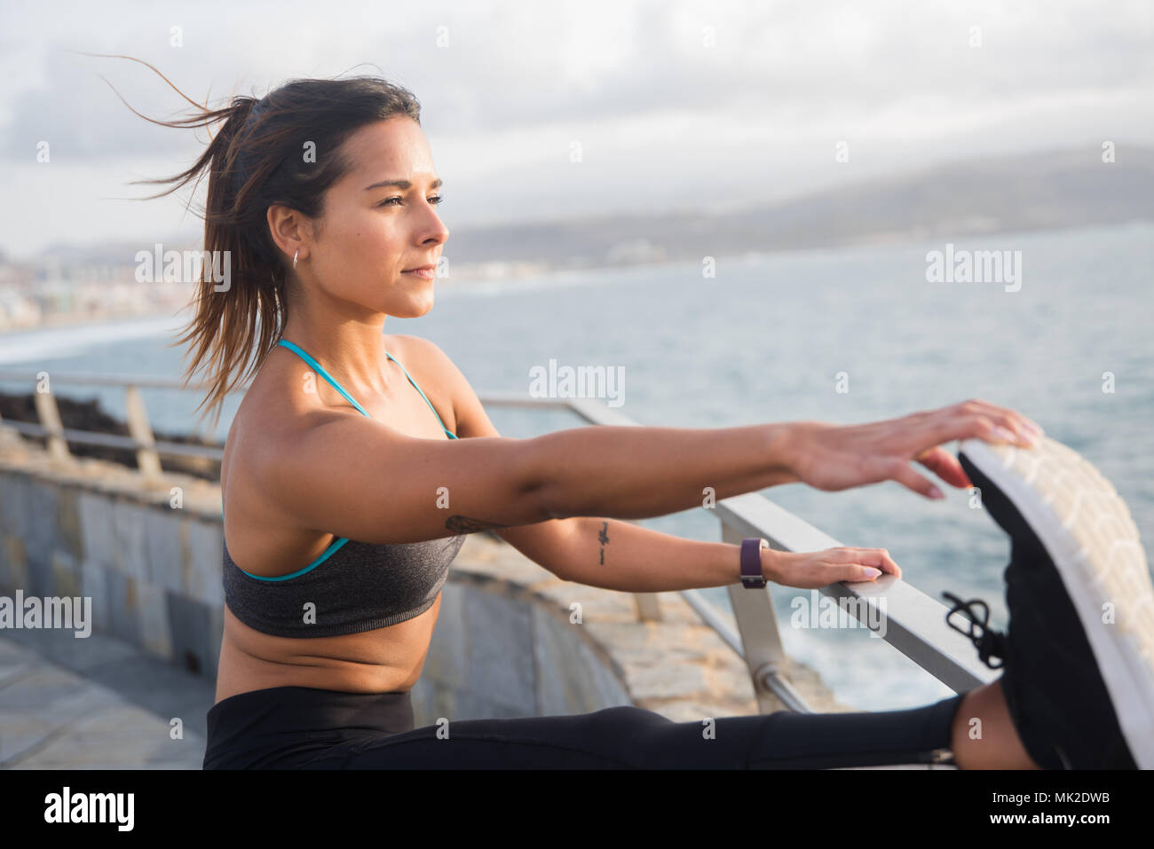 Una bella giovane donna dal lato del mare non tratti fitness in collant e serbatoio superiore con il sole sulla sua pelle Foto Stock