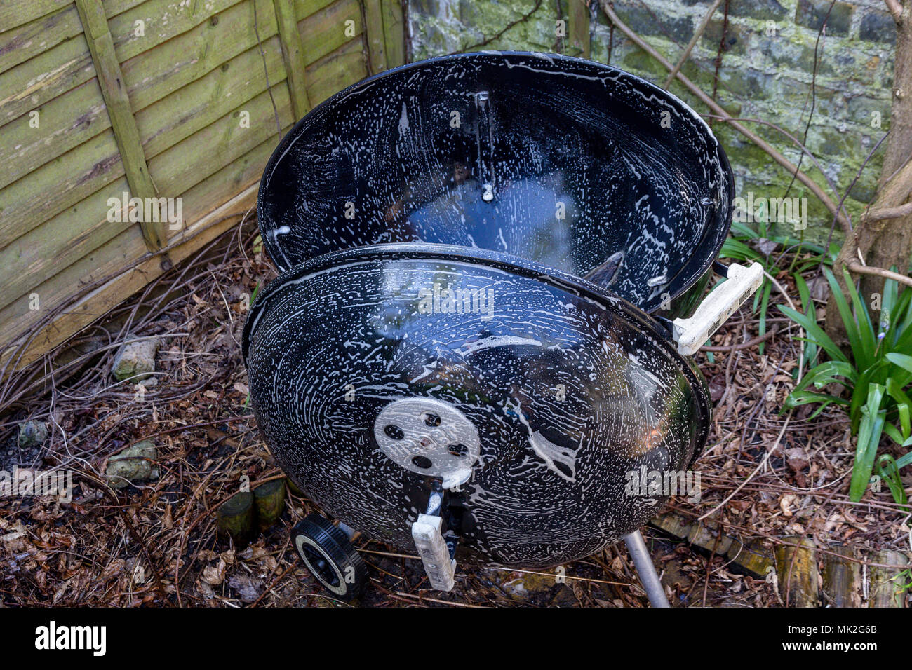 Pulizia di un bollitore barbecue a tamburo con acqua saponata Foto Stock