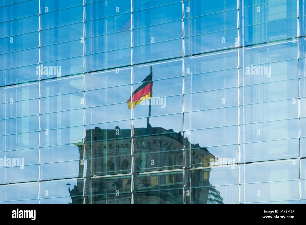 La riflessione della bandiera tedesca sul Reichstag in una moderna facciata di vetro Foto Stock