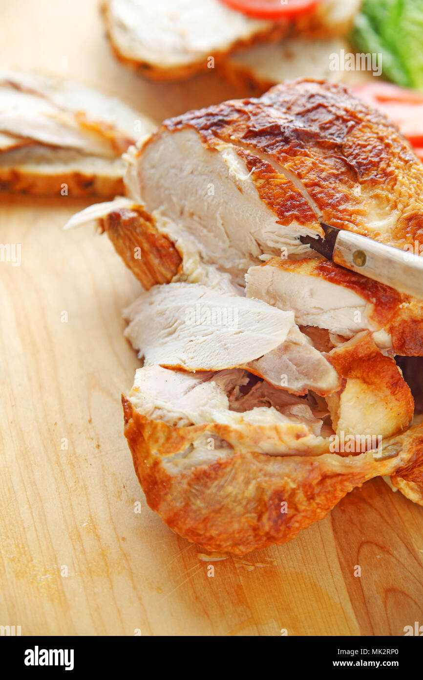 Un acquistato rotisserie pollo arrosto con il coltello sul tagliere con spazio per il testo Foto Stock