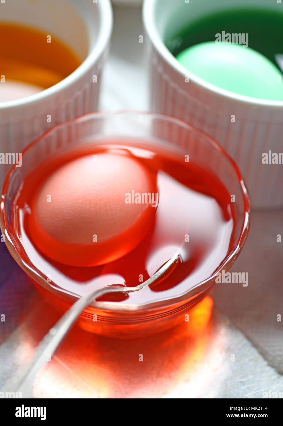 Uova venga tinto in verde e arancione in vari piatti con cucchiaio Foto Stock