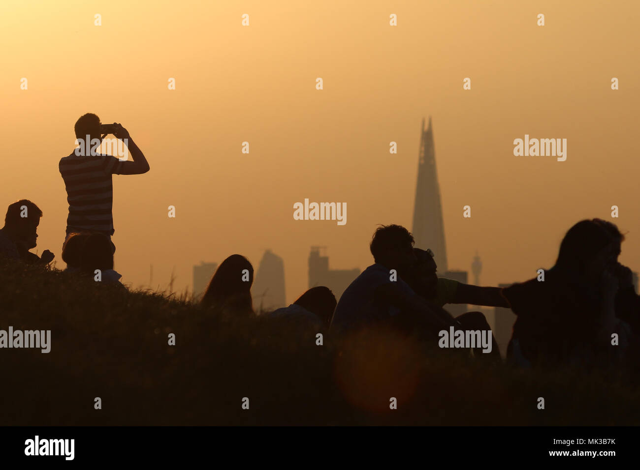 Greenwich, Regno Unito. Il 6 maggio, 2018. Il sole visto impostazione dietro una skyline di Londra da Greenwich Park a fine di Bank Holiday Domenica. Come il sole è andato giù e si è visto passare direttamente dietro il coccio. Rob Powell/Alamy Live News Foto Stock