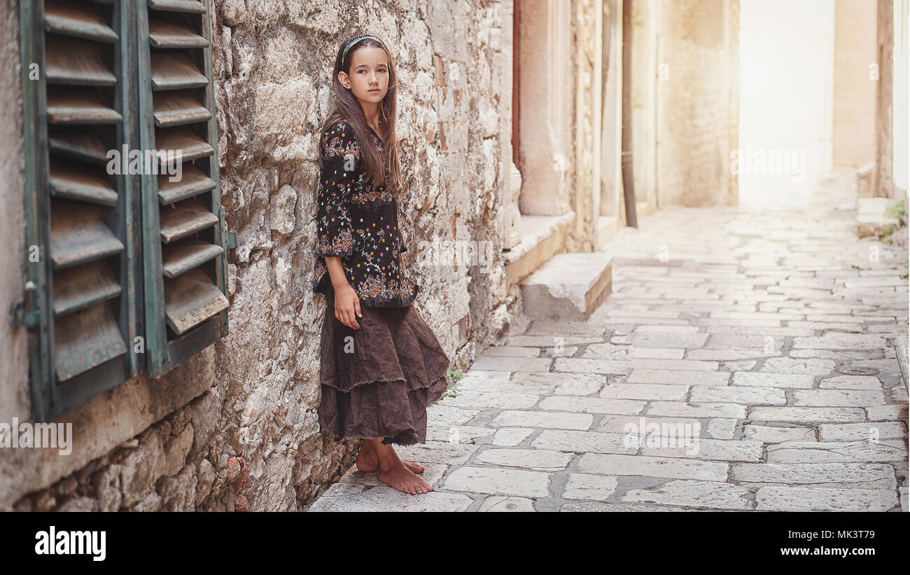 Incantevole piccola ragazza camminare lungo antiche strade di pietra nella parte vecchia della citta'. Foto Stock