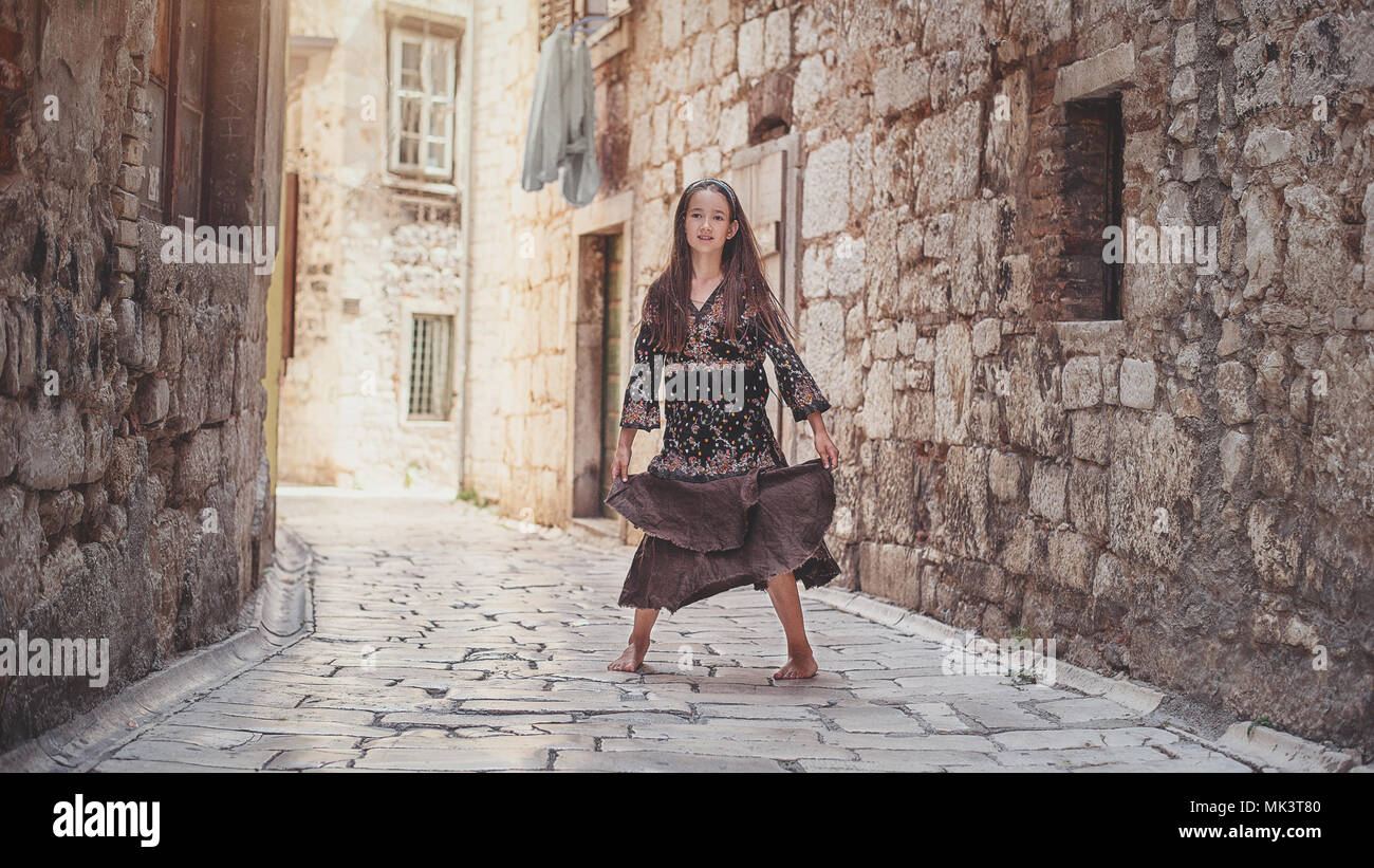 Incantevole piccola ragazza camminare lungo antiche strade di pietra nella parte vecchia della citta'. Foto Stock