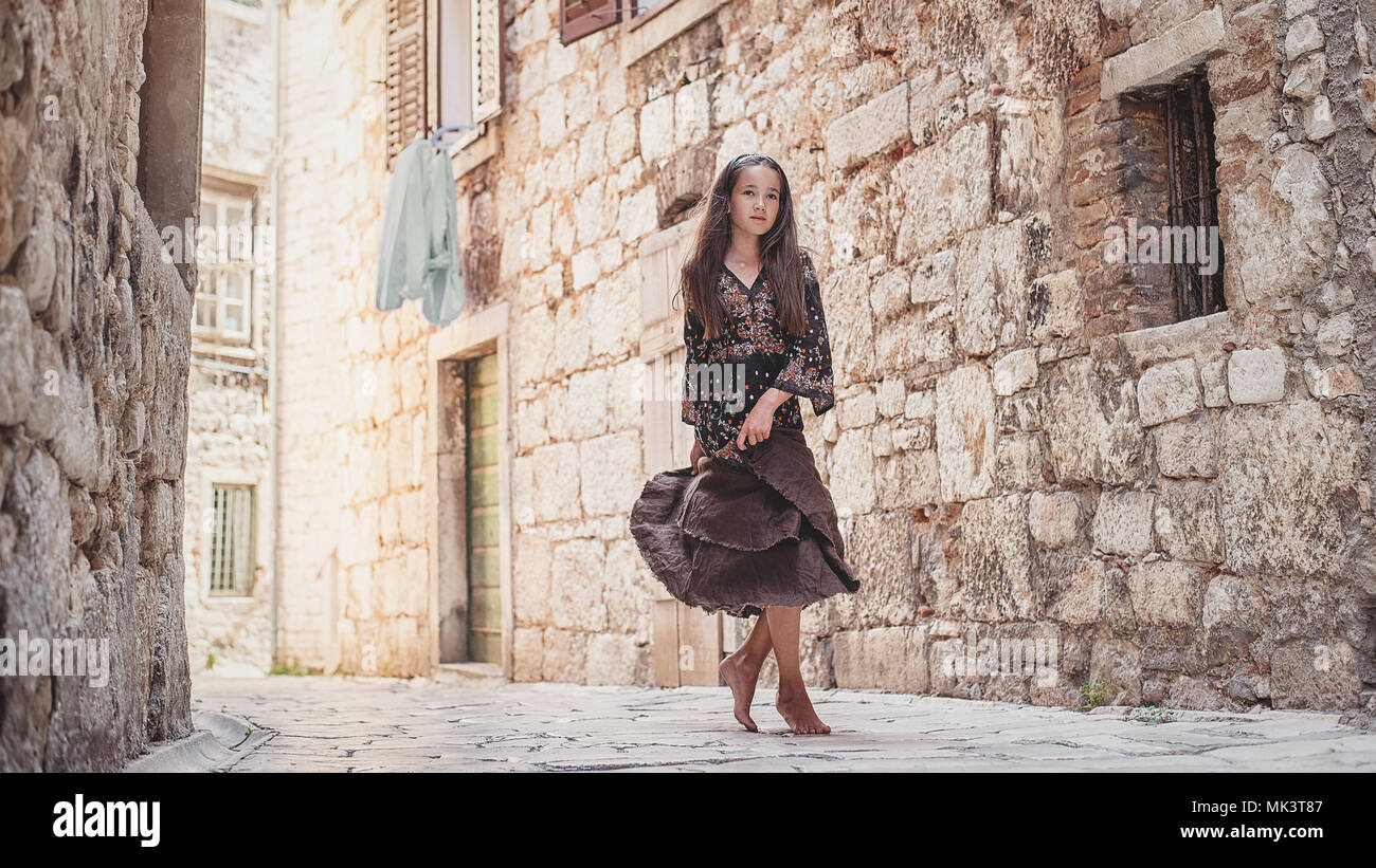 Incantevole piccola ragazza camminare lungo antiche strade di pietra nella parte vecchia della citta'. Foto Stock